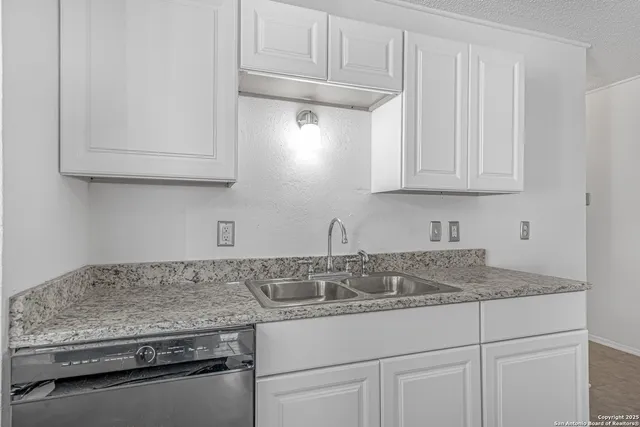 a kitchen with granite countertop white cabinets and a stove