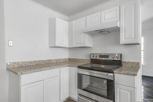 a kitchen with granite countertop a stove sink and cabinets