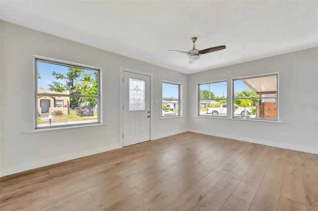 a view of an empty room with a window and wooden floor