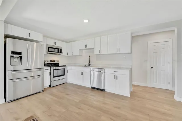 a kitchen with white cabinets and stainless steel appliances