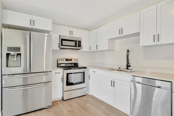 a kitchen with stainless steel appliances granite countertop white cabinets a sink a stove a refrigerator and white cabinets