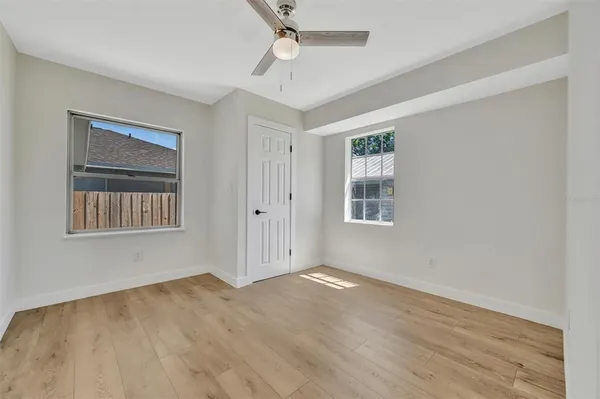 a view of an empty room with wooden floor and a window