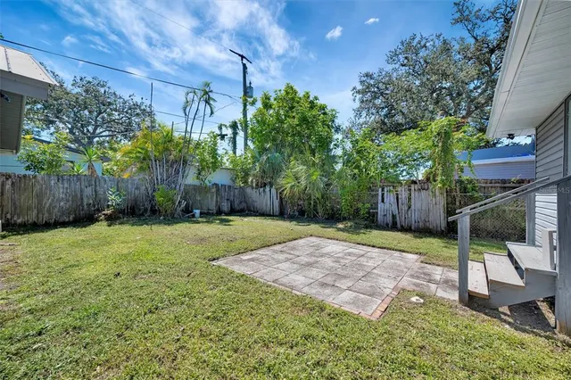 a view of a backyard with large trees and wooden fence