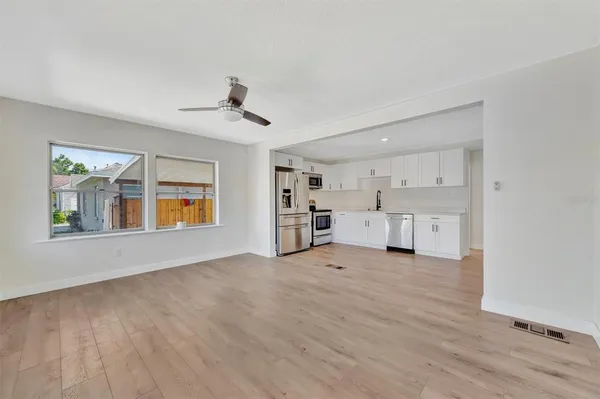 a view of an empty room with a window and wooden floor
