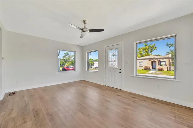a view of an empty room with window and wooden floor