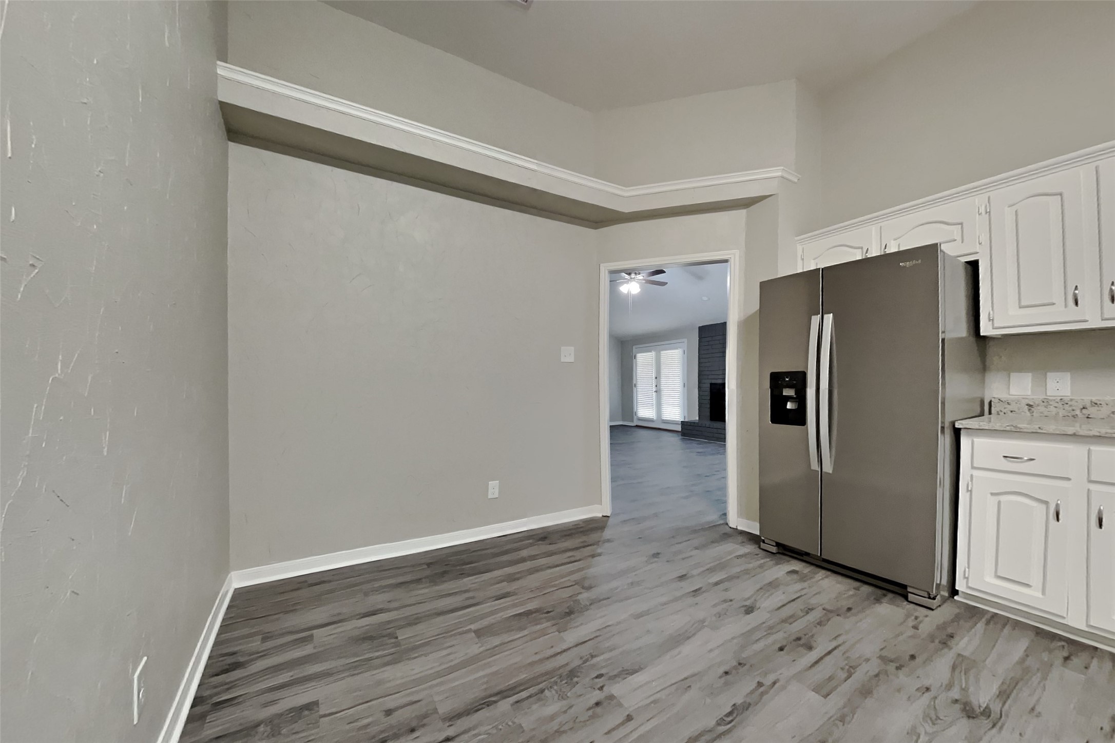 6818 White Tail Drive Spring, TX 77379 - Photo 8 of 24 a view of a refrigerator in kitchen and an empty room with wooden floor