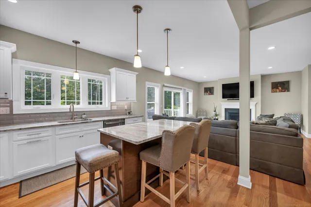 a kitchen with stainless steel appliances granite countertop a stove top oven a refrigerator a sink a dining table and chairs with wooden floor