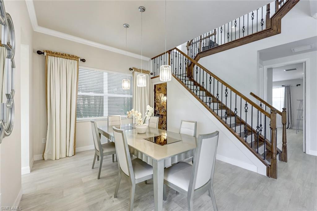 6582 Monterey Point Naples, FL 34105 - Photo 11 of 28 a dining room with wooden floor a chandelier a wooden table and chairs