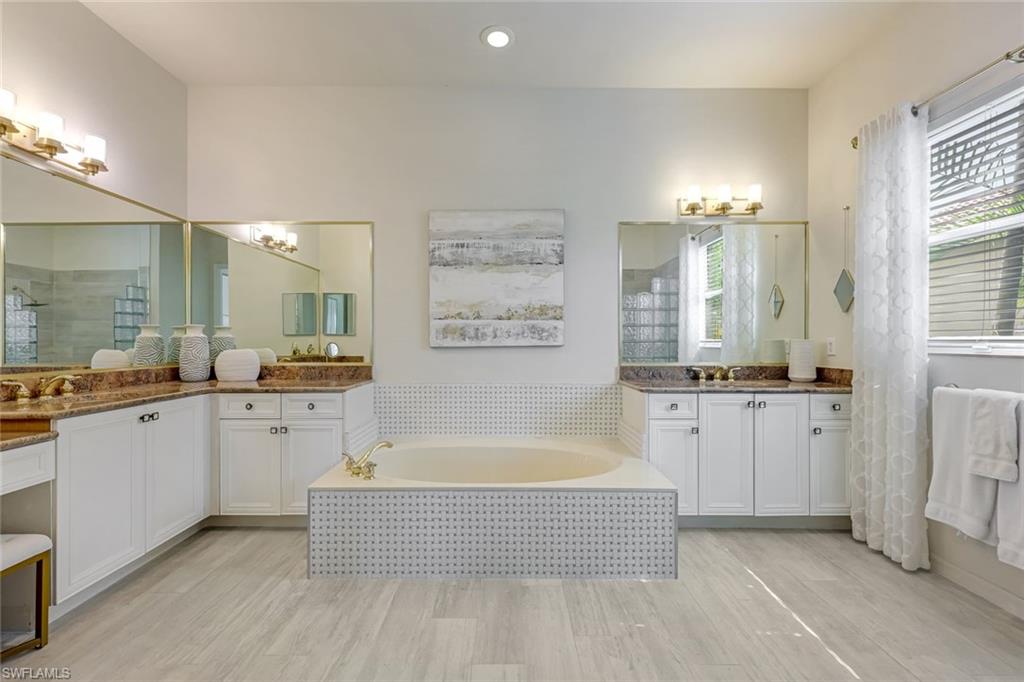 6582 Monterey Point Naples, FL 34105 - Photo 15 of 28 a bathroom with a tub a double vanity sink a window and a mirror