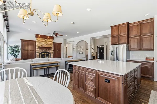 a kitchen with stainless steel appliances granite countertop a white stove top oven a sink a dining table and chairs with wooden floor