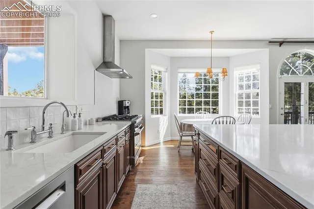 a kitchen with stainless steel appliances granite countertop a sink a stove and a wooden floor