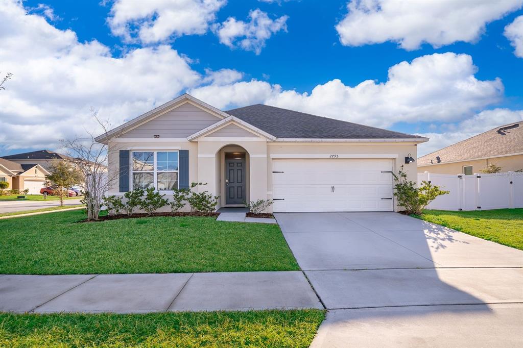 a view of a white house next to a yard and a large tree