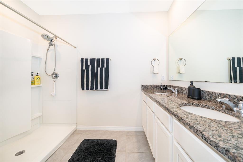 2795 Harmonia Hammock Road St. Cloud, FL 34773 - Photo 15 of 30 a bathroom with a granite countertop sink a mirror and shower