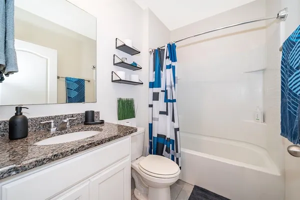 a bathroom with a granite countertop sink a toilet and a bathtub