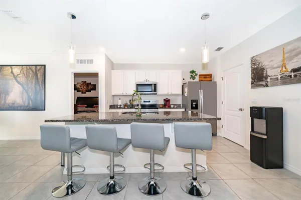 a kitchen with stainless steel appliances kitchen island granite countertop a dining table chairs and a refrigerator