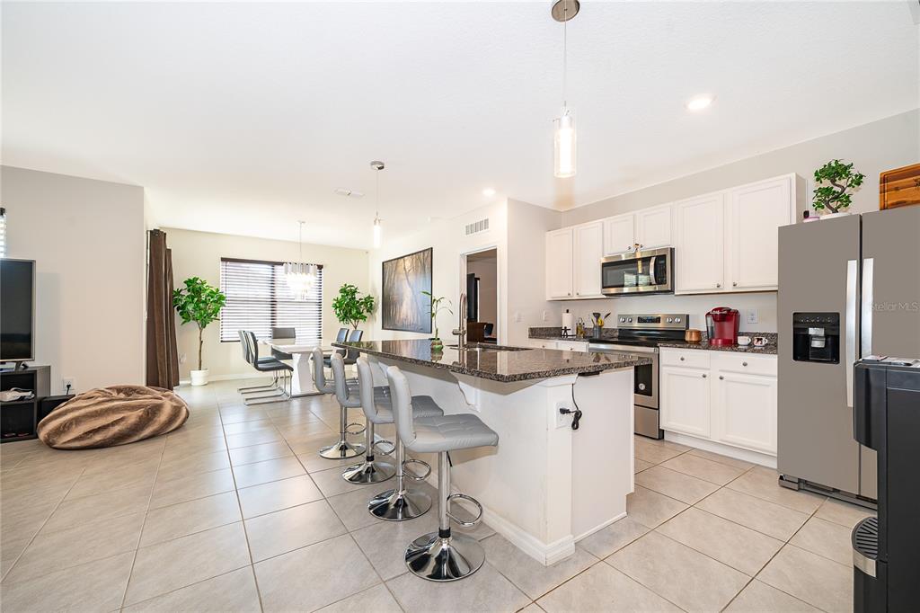 2795 Harmonia Hammock Road St. Cloud, FL 34773 - Photo 6 of 30 a kitchen with stainless steel appliances kitchen island granite countertop a refrigerator oven a sink a dining table and chairs with wooden floor