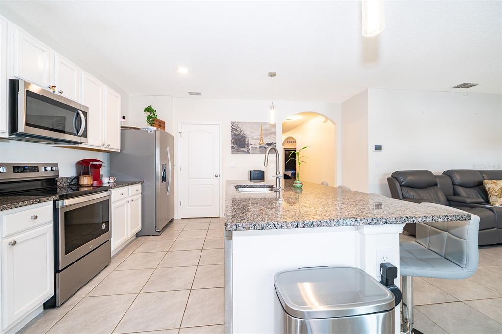 2795 Harmonia Hammock Road St. Cloud, FL 34773 - Photo 7 of 30 a kitchen with stainless steel appliances granite countertop a sink a stove a microwave a refrigerator and cabinets