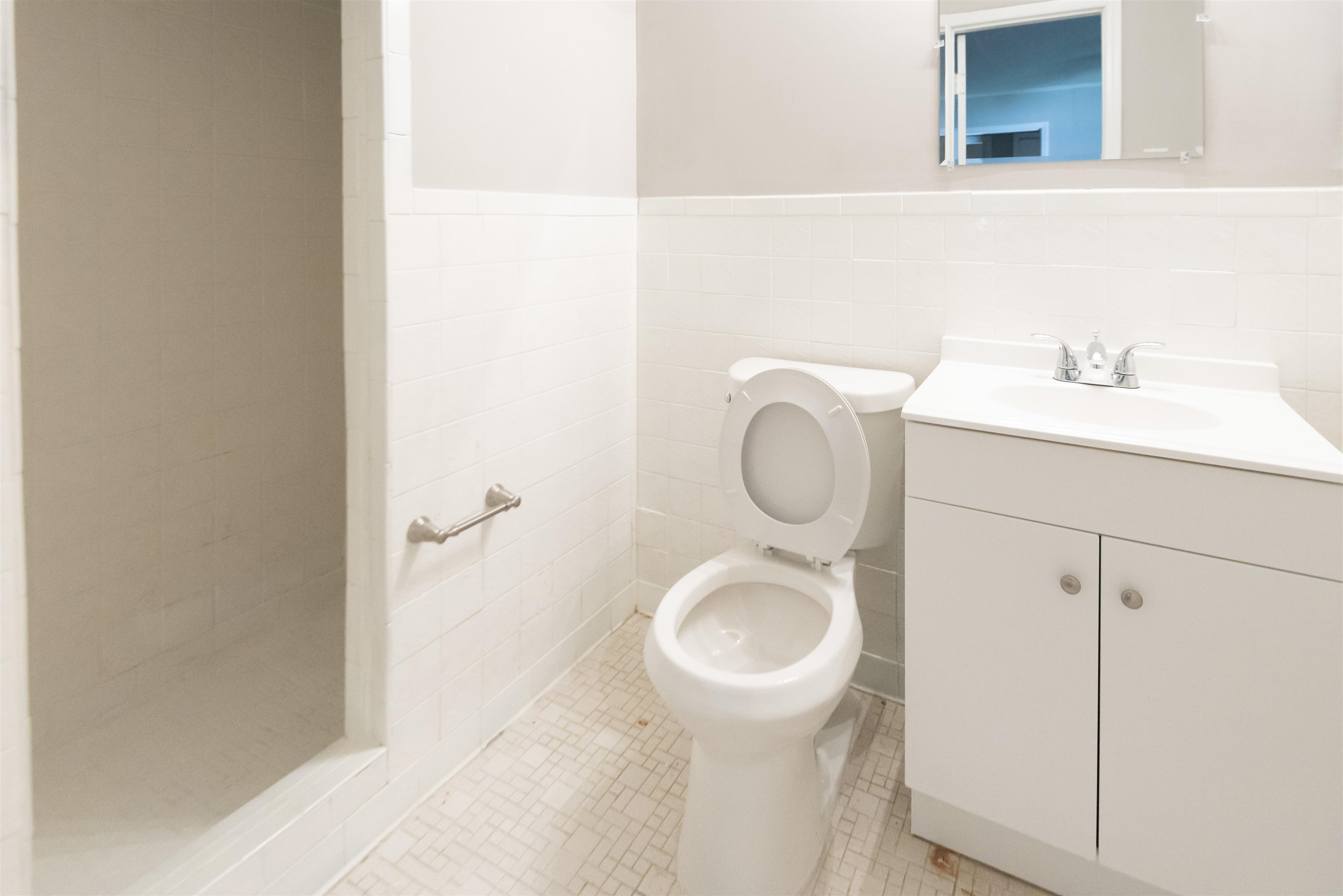 4399 Pepper Tree Road Memphis, TN 38109 - Photo 10 of 14 White subway tile wainscoting, white floor tile, white vanity with integrated sink, chrome faucet, and a wall-mounted mirror