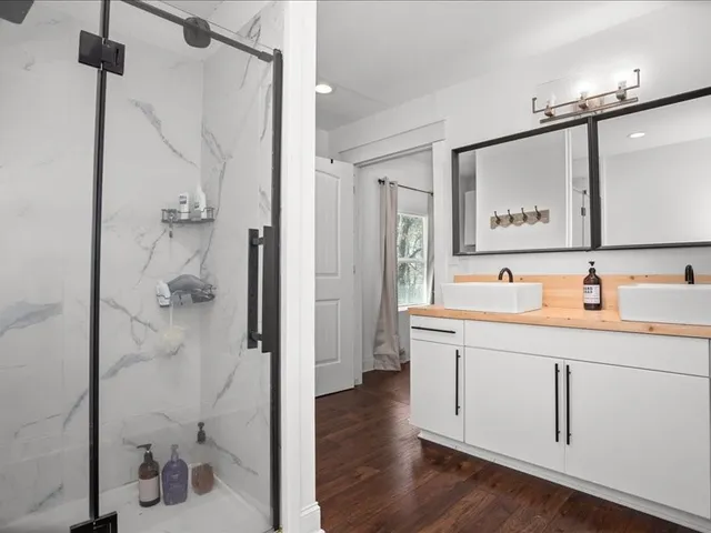 a bathroom with a granite countertop sink mirror and a shower