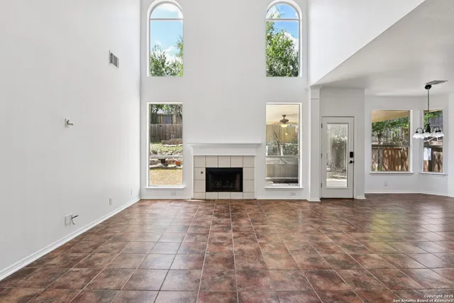 an empty room with windows and fireplace