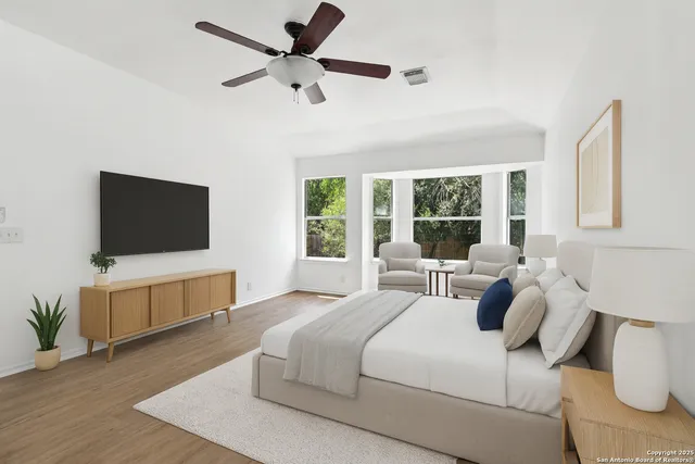 an empty room with wooden floor fan and windows