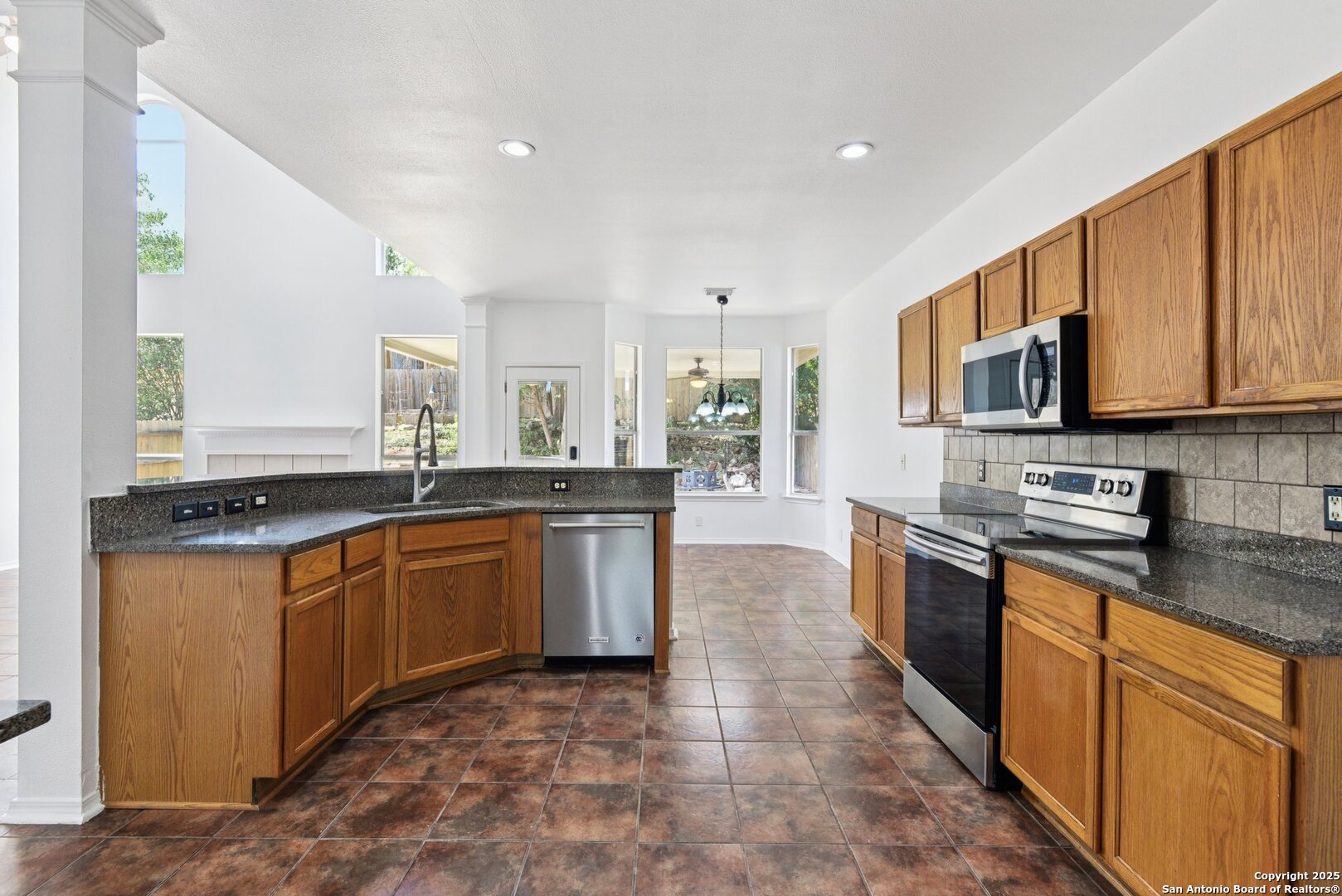 21510 Rio Colorado San Antonio, TX 78259 - Photo 6 of 42 a large kitchen with stainless steel appliances granite countertop a stove top oven a sink dishwasher a dining table and chairs with wooden floor