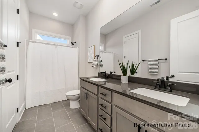 a bathroom with a granite countertop sink a toilet a mirror and shower