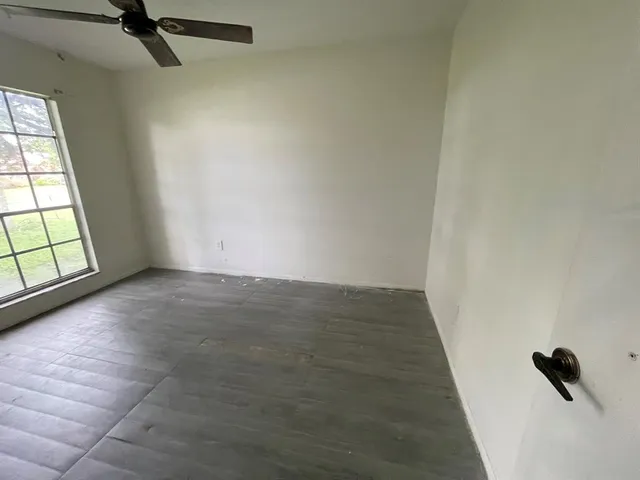 en empty room with windows and ceiling fan