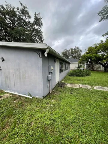 a backyard of a house with lawn chairs plants and tree