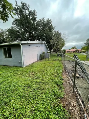 a backyard of a house with plants and large tree