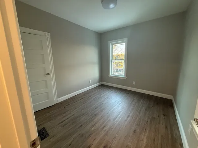 an empty room with wooden floor and window