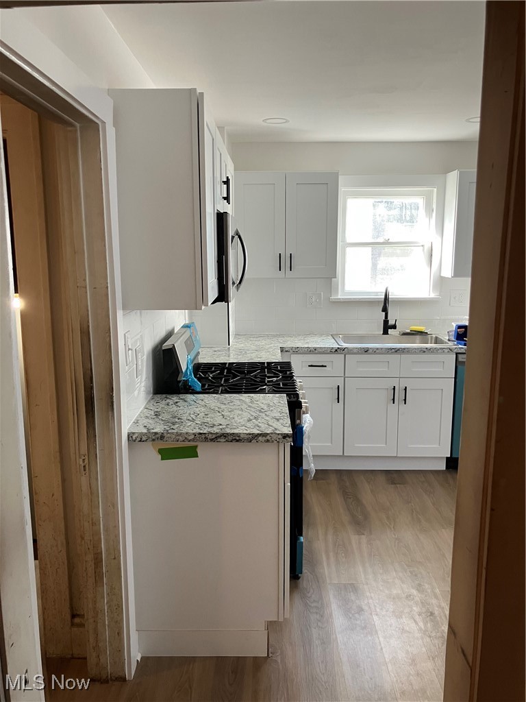 1058 Pembrook Road Cleveland Heights, OH 44121 - Photo 12 of 39 Kitchen with range, light wood-style floors, backsplash, light stone counters, and white cabinetry