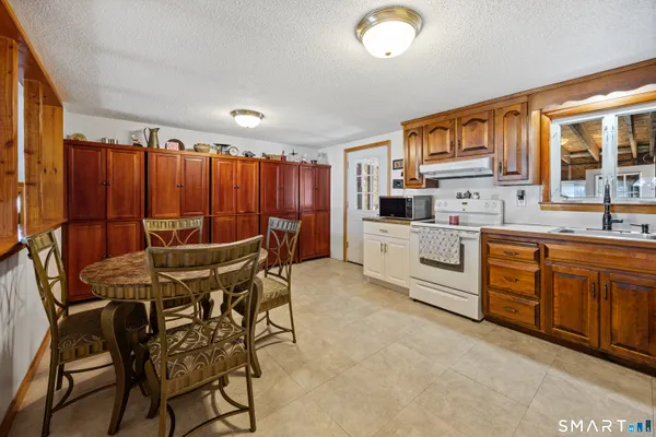 a kitchen with stainless steel appliances kitchen island granite countertop a table chairs sink and cabinets