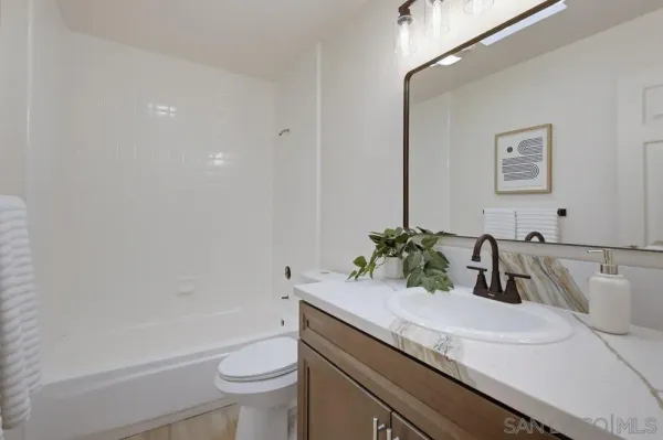 a bathroom with a granite countertop sink a toilet and a mirror