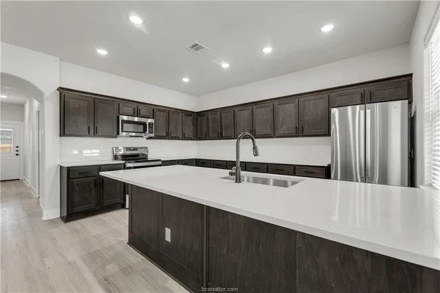 a kitchen with stainless steel appliances granite countertop a sink stove and refrigerator