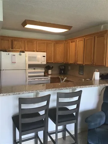 a kitchen with stainless steel appliances granite countertop a table chairs sink and cabinets