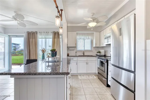 a kitchen with granite countertop white cabinets appliances and a window