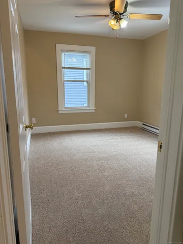 an empty room with a chandelier fan and windows
