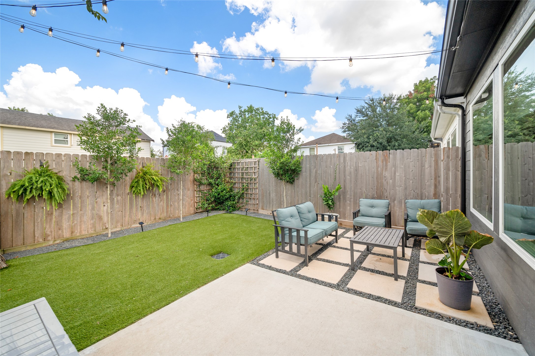 4603 Terry Street Houston, TX 77009 - Photo 21 of 41 Charming backyard retreat featuring a cozy seating area on a modern paved patio, surrounded by lush greenery and privacy fencing, creating an additional downstairs living area.