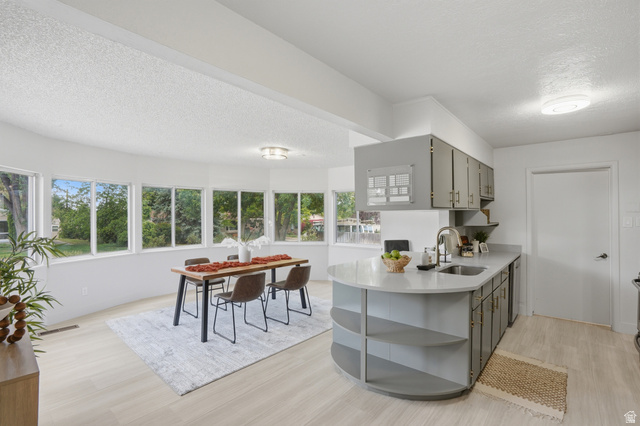 6889 South Village Road Salt Lake City, UT 84121 - Photo 12 of 44 Open-concept living space with LVP Tile flooring, bay of windows, and a kitchen island with integrated shelving