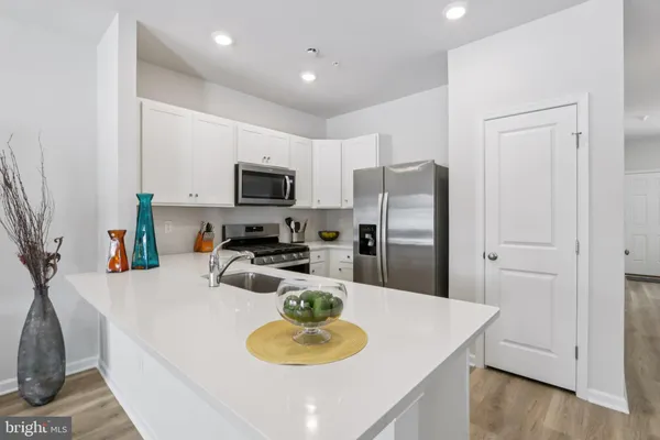 a kitchen with stainless steel appliances granite countertop a sink a microwave a refrigerator and white cabinets