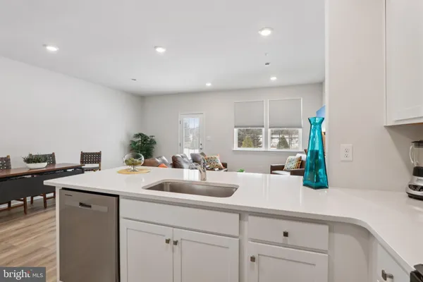 a kitchen with a sink dishwasher and white cabinets with wooden floor