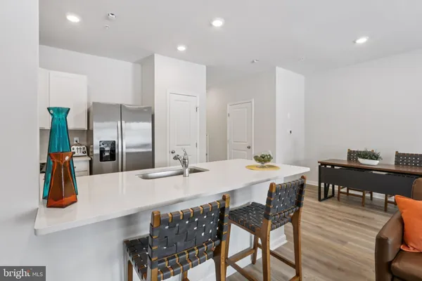 a dining hall with stainless steel appliances kitchen island granite countertop a table chairs and a refrigerator
