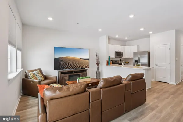 a living room with furniture and a flat screen tv with kitchen view