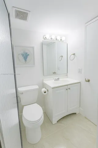 a bathroom with a toilet a sink a mirror a vanity and shower