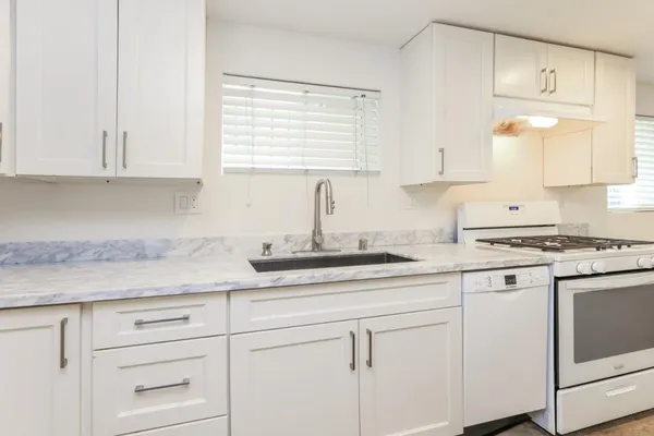 a kitchen with granite countertop white cabinets and white appliances