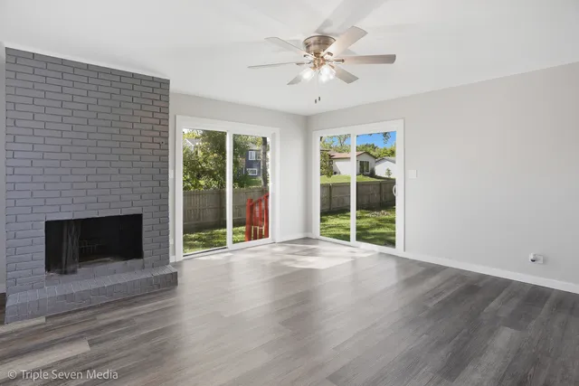 a view of an empty room with wooden floor fireplace and a window