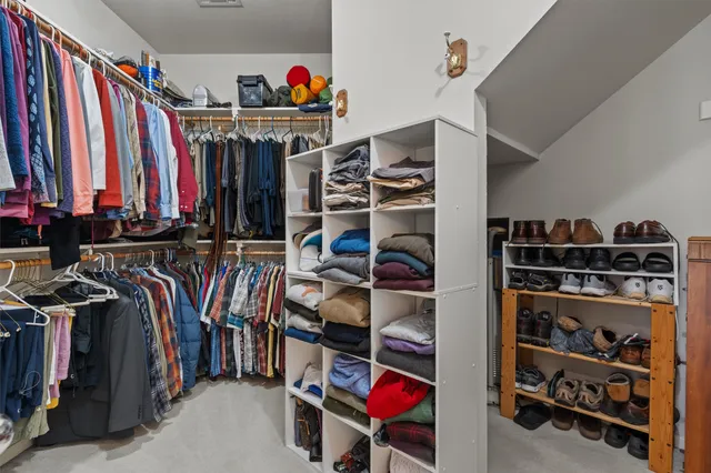 a view of walk in closet with clothes and shoes