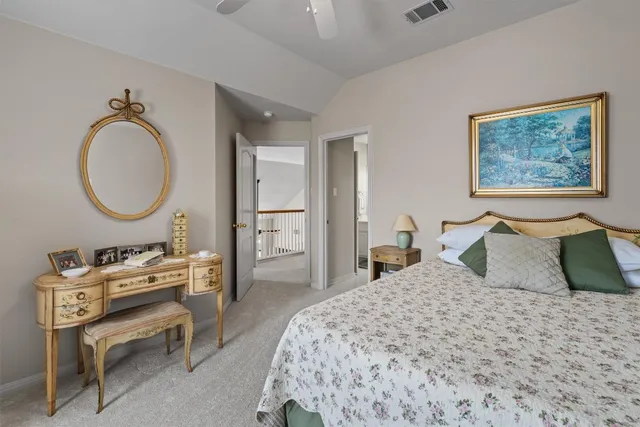 a bedroom with a bed a mirror and a lamp on dresser