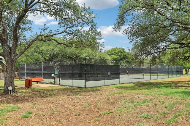 a view of a tennis ground with large trees